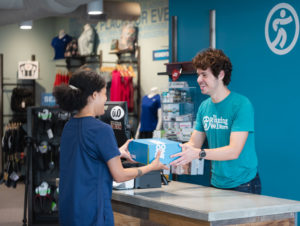 woman checking out at the running well store after purchasing running shoes in kansas city
