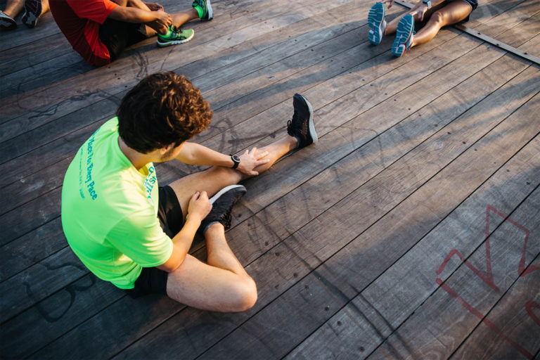 person stretching for extra flexibility and to protect their knees before a group run