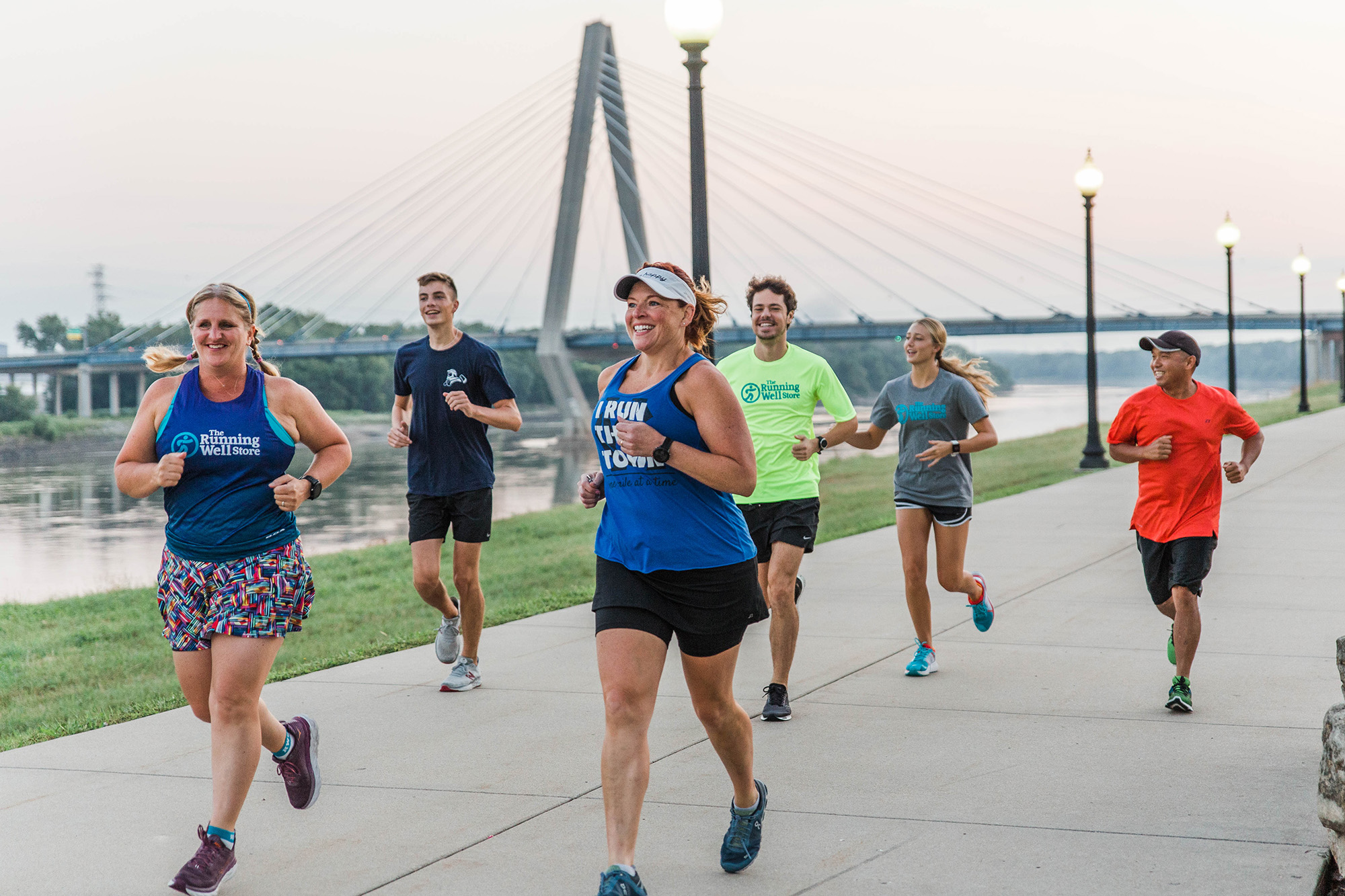 group of runners on a concrete path along the river in kansas city