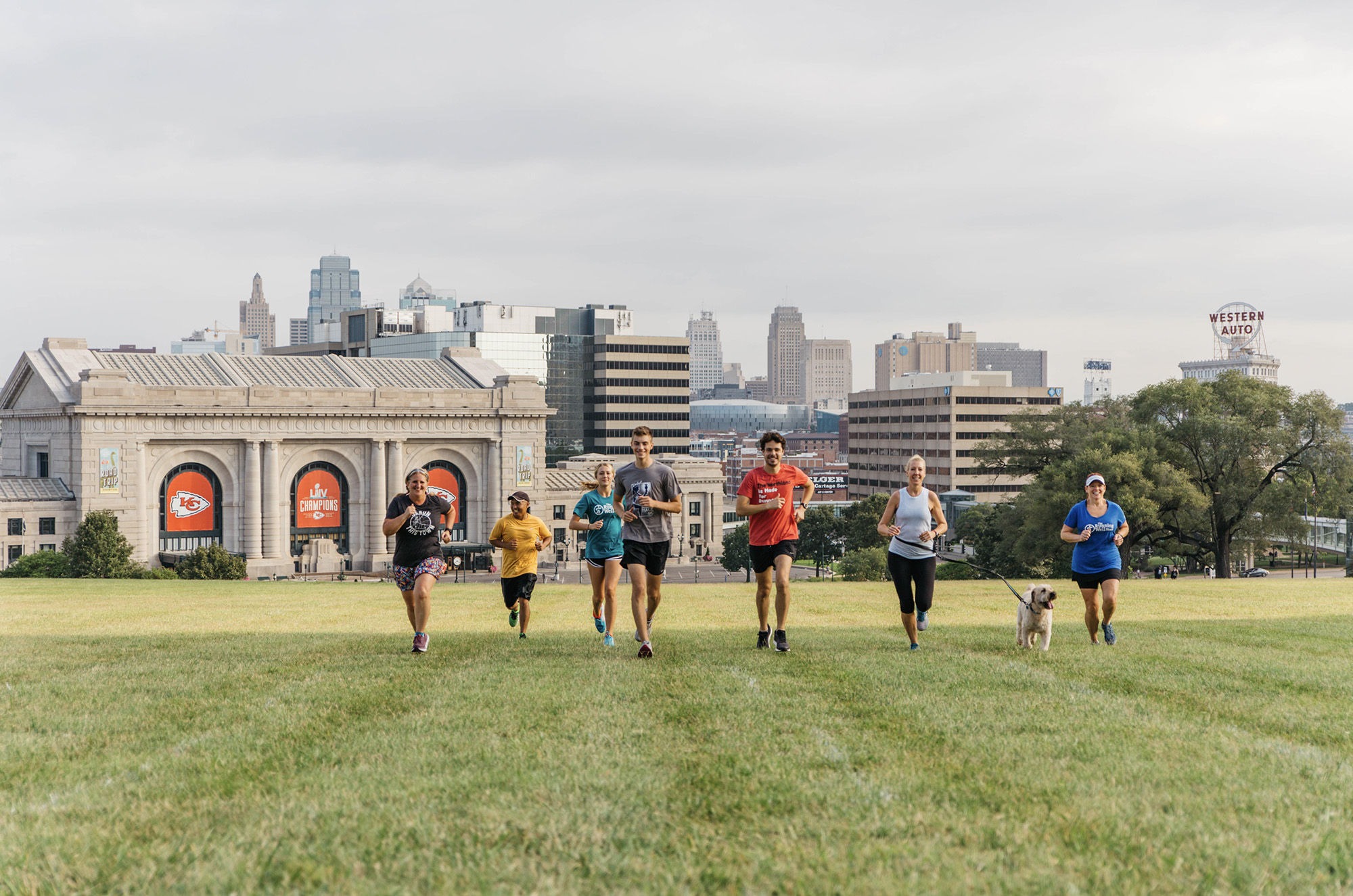 diverse group of runners in front of the kansas city skyline