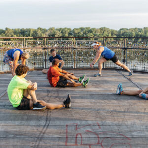 group of friends stretching before a run and discussing their running shoes in the river market of kansas city